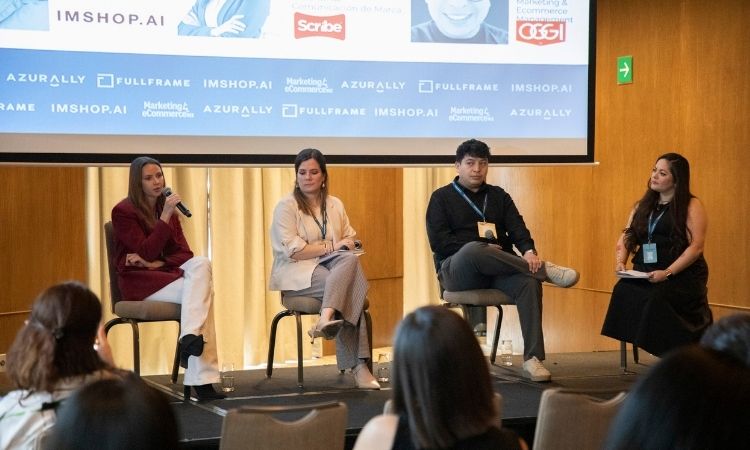 Panel de cuatro oradores sentados; una mujer habla por un micrófono de mano mientras los demás escuchan en un escenario de conferencias con una pancarta de patrocinador proyectada y público sentado. Contexto: sala con paneles de madera. Texto: IMSHOP.AI, Scribe, AZURALLY, FULLFRAME, IMSHOP.AI, Marketing y comercio electrónico.