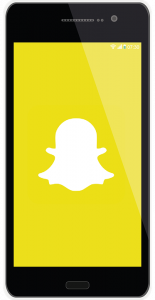 El tel&eacute;fono inteligente muestra un logotipo blanco fantasma de Snapchat centrado en una pantalla amarilla brillante; se ven el cuerpo y el marco del tel&eacute;fono, con una barra de estado que muestra la hora "07:30" y peque&ntilde;os iconos del sistema.