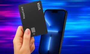 Tarjeta RappiCard negra sostenida en la mano (texto: "RappiCard", "VISA") tocada cerca de la pantalla de un teléfono inteligente, sobre franjas de luz horizontales azules y magenta; se aprecian el chip EMV y el símbolo de pago sin contacto.